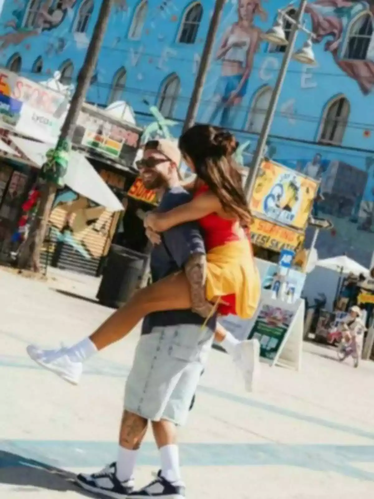Parella jove gaudint d’un passeig per Venice Beach mentre ell la porta a l’esquena i tots dos somriuen. Parella jove gaudint d’un passeig per Venice Beach mentre ell la porta a l’esquena i tots dos somriuen.