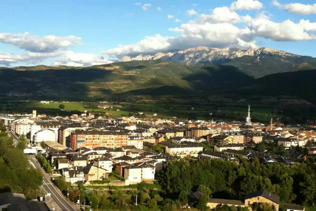 Panoramic view of a city surrounded by green mountains under a blue sky with white clouds Panoramic view of a city surrounded by green mountains under a blue sky with white clouds