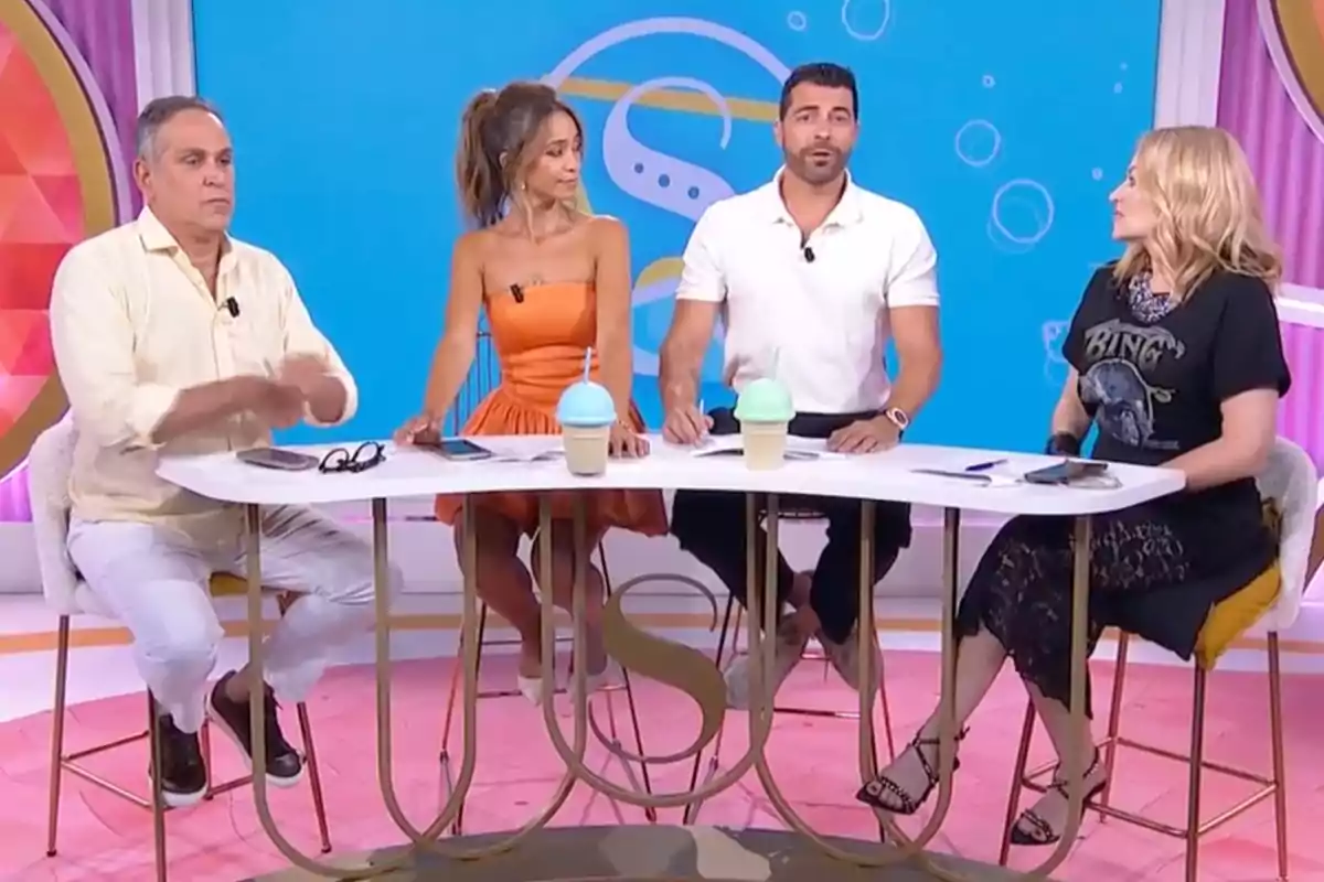 Quatre persones assegudes al voltant d’una taula en un plató de televisió colorit, amb begudes i objectes personals sobre la taula, totes conversant i mirant en diferents direccions. Captura de ‘Socialité’ Quatre persones assegudes al voltant d’una taula en un plató de televisió colorit, amb begudes i objectes personals sobre la taula, totes conversant i mirant en diferents direccions. Captura de ‘Socialité’
