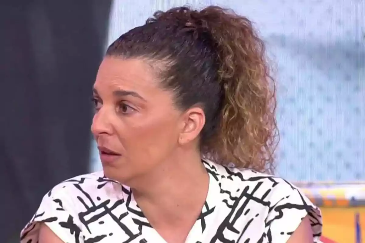 Pla curt de la Tamara, germana de la Michu, amb els cabells arrissats i recollits en una cua mirant cap a l’esquerra amb expressió seriosa, vestida amb una brusa blanca de ratlles negres en un plató de televisió. Pla curt de la Tamara, germana de la Michu, amb els cabells arrissats i recollits en una cua mirant cap a l’esquerra amb expressió seriosa, vestida amb una brusa blanca de ratlles negres en un plató de televisió.