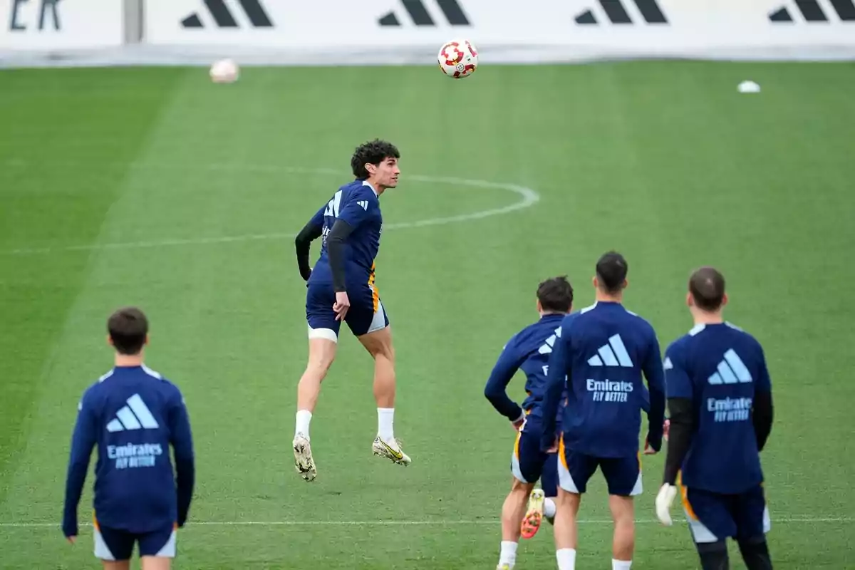 Soccer players training on a grass field while one of them jumps to head a ball in front of his teammates. Soccer players training on a grass field while one of them jumps to head a ball in front of his teammates.