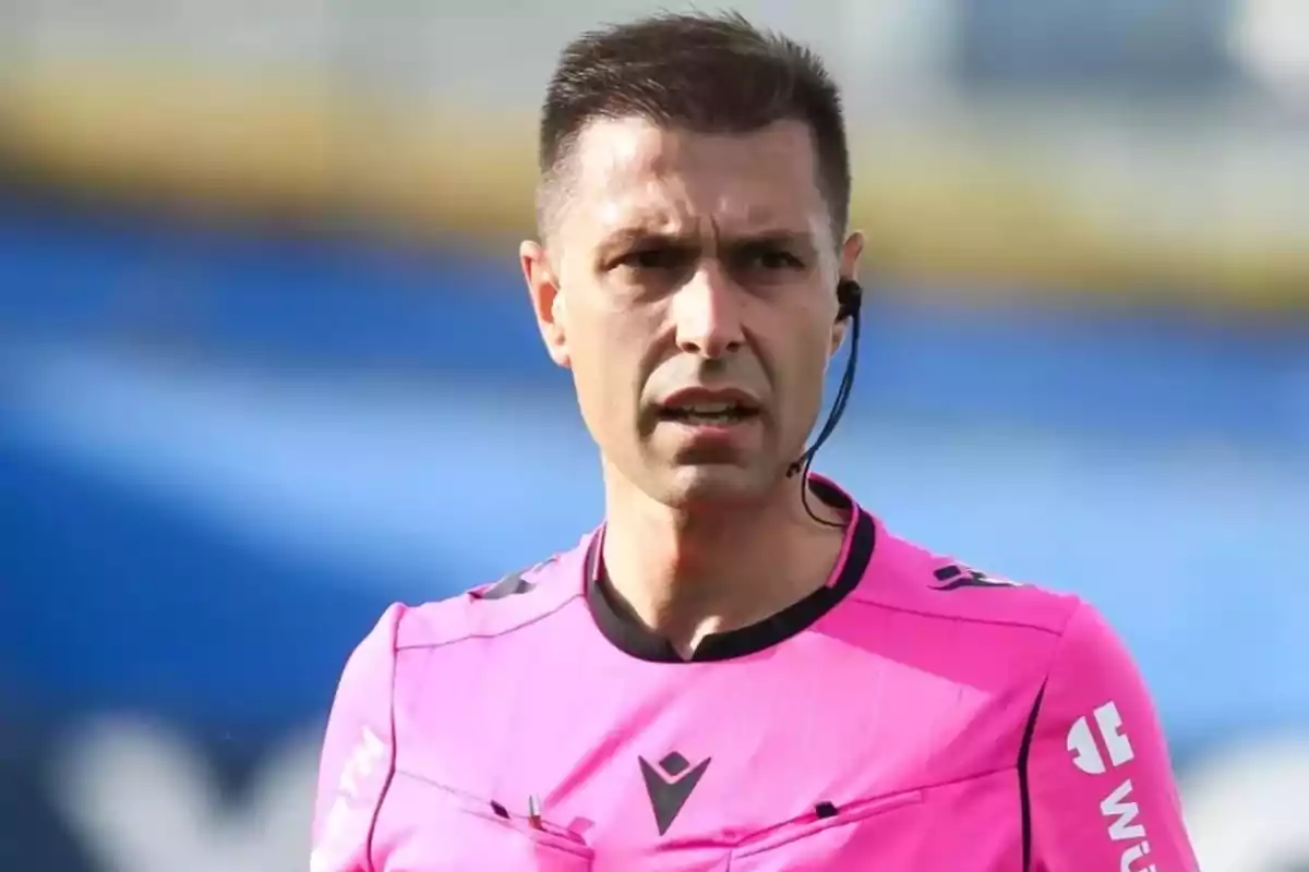 Árbitro de fútbol vistiendo uniforme rosa y usando un auricular en un estadio Árbitro de fútbol vistiendo uniforme rosa y usando un auricular en un estadio
