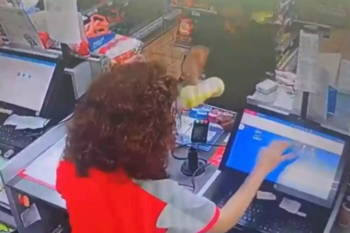 Cajera atendiendo a un cliente en una tienda mientras utiliza la pantalla de una computadora