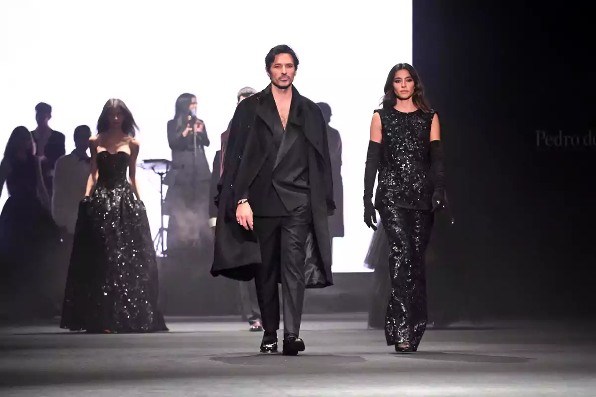 Models desfilant en una passarel·la de moda amb elegants vestits negres i un fons il·luminat Models desfilant en una passarel·la de moda amb elegants vestits negres i un fons il·luminat