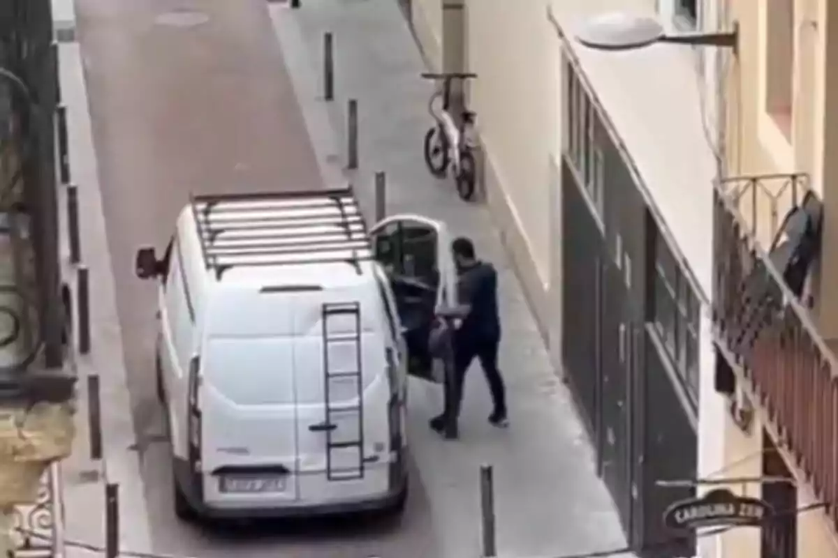 Home pujant a una furgoneta blanca estacionada en un carrer estret al costat d’un edifici
