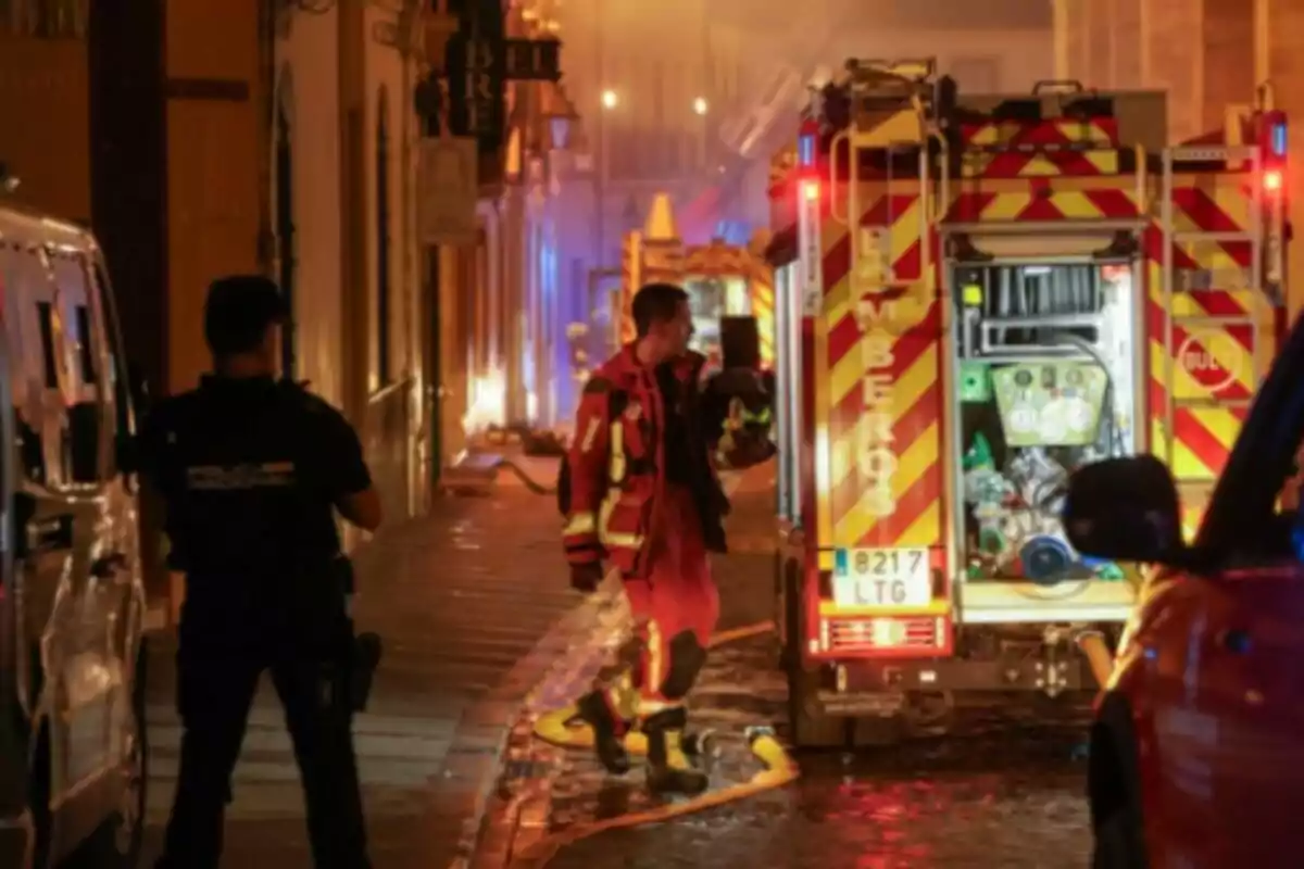 Un bomber i un policia treballen en un carrer durant una emergència nocturna, a l’incendi de la Mesquita de Còrdova, amb camions de bombers i llums enceses. Un bomber i un policia treballen en un carrer durant una emergència nocturna, a l’incendi de la Mesquita de Còrdova, amb camions de bombers i llums enceses.