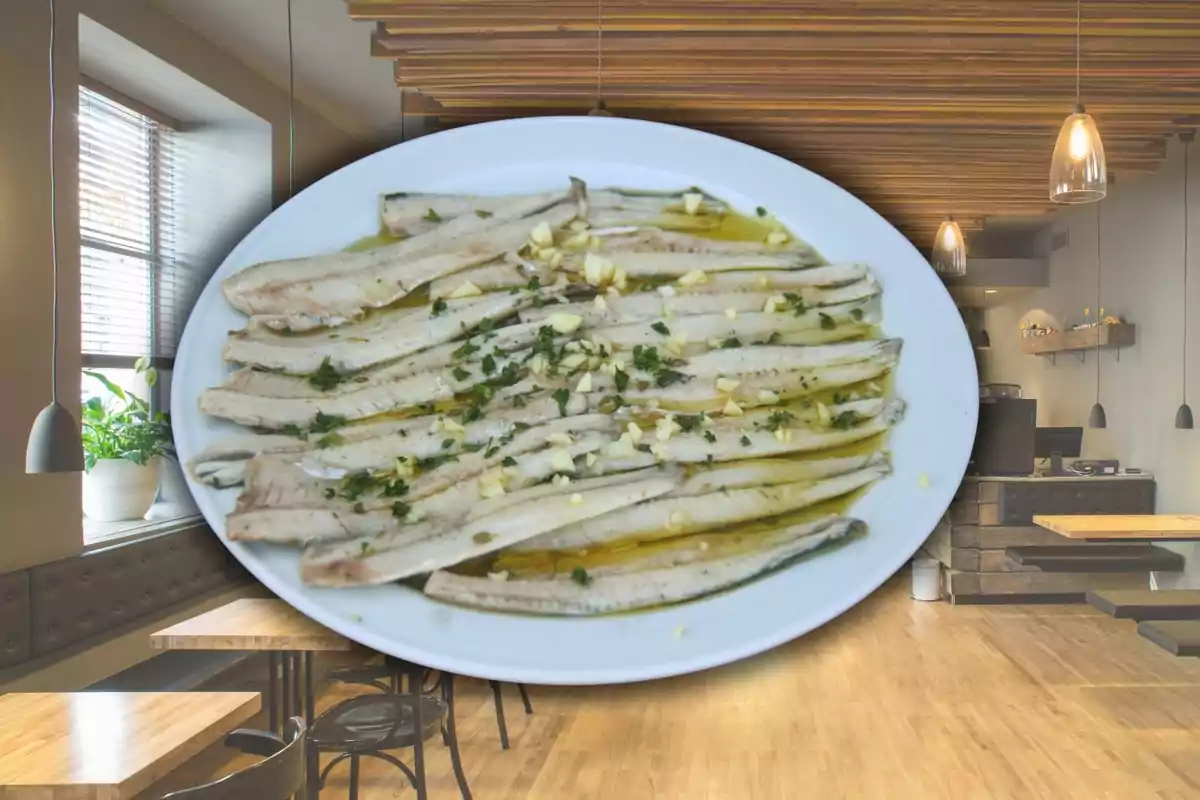 Plat d’anxoves en vinagre amb all i julivert servit en un restaurant modern i lluminós Plat d’anxoves en vinagre amb all i julivert servit en un restaurant modern i lluminós
