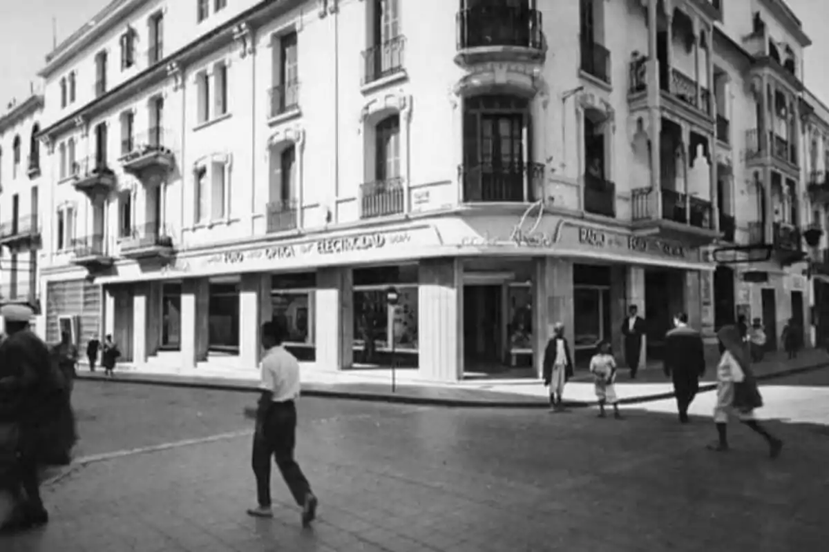 Persones caminant per una cantonada en una ciutat amb un edifici antic de diversos pisos i balcons Persones caminant per una cantonada en una ciutat amb un edifici antic de diversos pisos i balcons
