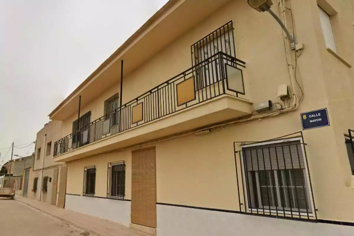 Fachada de una casa de dos pisos con balcones y ventanas enrejadas en una calle tranquila, se trata de la calle mayor de Albatana. Fachada de una casa de dos pisos con balcones y ventanas enrejadas en una calle tranquila, se trata de la calle mayor de Albatana.
