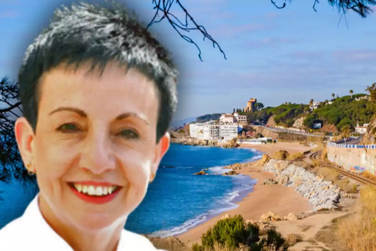 Mujer sonriente con cabello corto al frente de una playa con mar azul y edificios al fondo