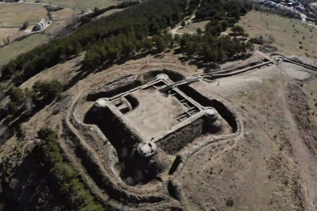 Vista aérea de una antigua fortaleza de piedra rodeada de vegetación y caminos en una zona montañosa Vista aérea de una antigua fortaleza de piedra rodeada de vegetación y caminos en una zona montañosa