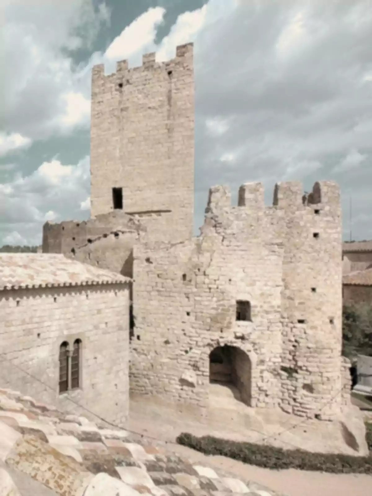 Antic castell de pedra amb torre principal i muralles parcialment enderrocades sota un cel ennuvolat Antic castell de pedra amb torre principal i muralles parcialment enderrocades sota un cel ennuvolat
