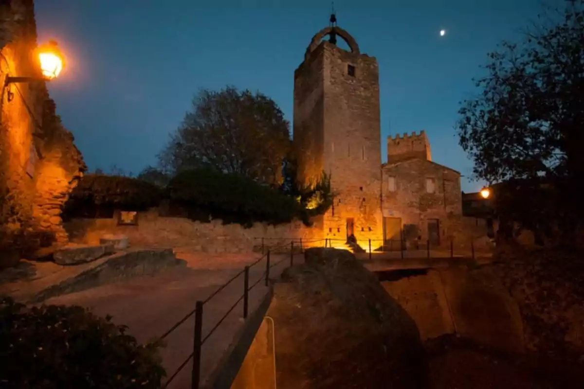 Torre de pedra il·luminada al capvespre amb fanals encesos i cel blau fosc Torre de pedra il·luminada al capvespre amb fanals encesos i cel blau fosc