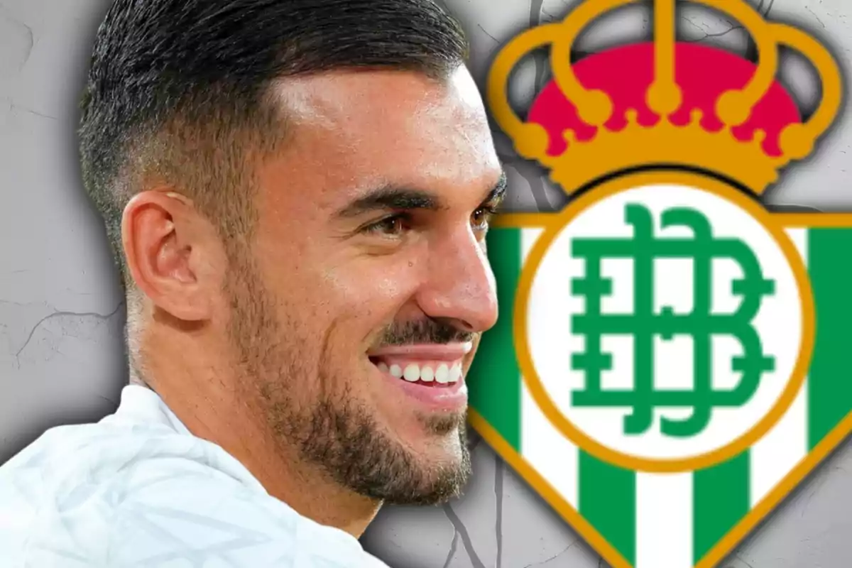 Hombre sonriente con barba frente al escudo del Real Betis