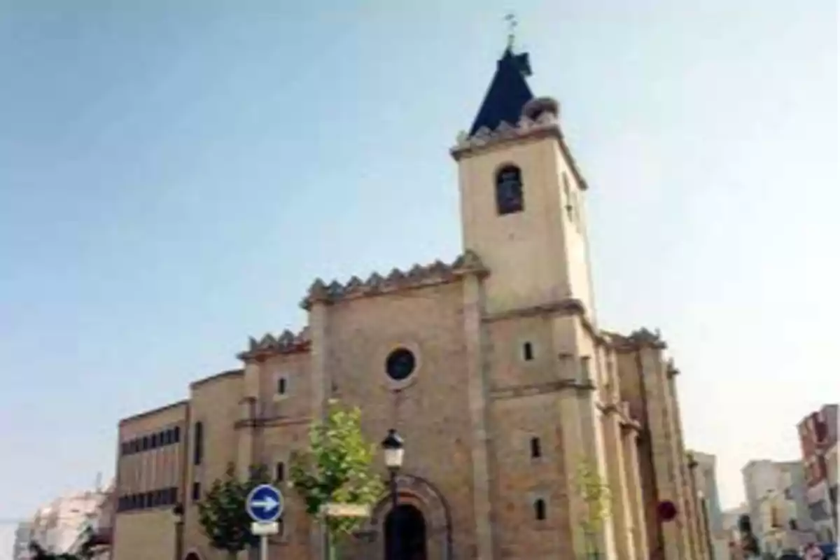 Iglesia antigua de piedra con torre campanario y techo oscuro en una ciudad bajo un cielo despejado Iglesia antigua de piedra con torre campanario y techo oscuro en una ciudad bajo un cielo despejado