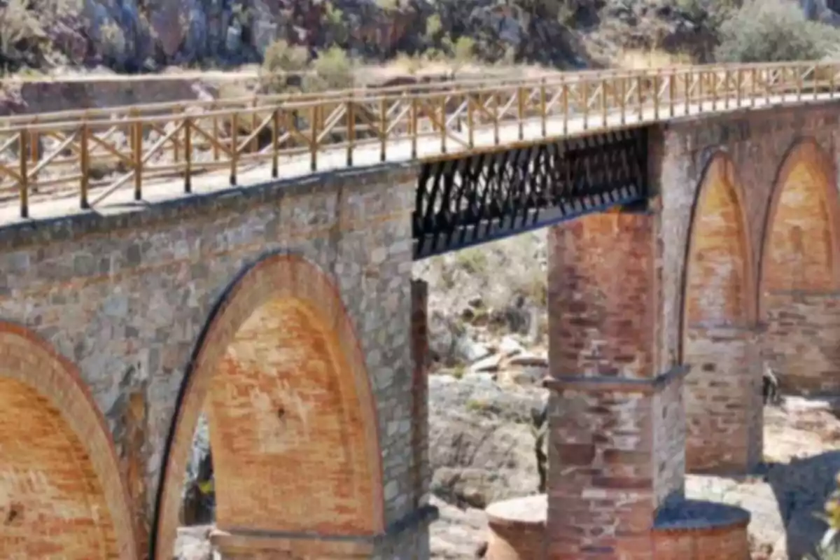 Pont antic de pedra i maó amb baranes de fusta en un entorn natural rocós Pont antic de pedra i maó amb baranes de fusta en un entorn natural rocós