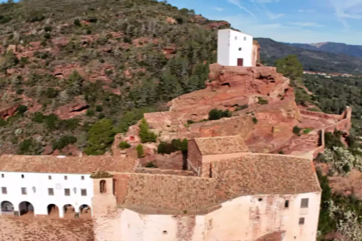 Vista panorámica de un monasterio con edificios de paredes blancas y tejados de teja rodeado de montañas y vegetación Vista panorámica de un monasterio con edificios de paredes blancas y tejados de teja rodeado de montañas y vegetación