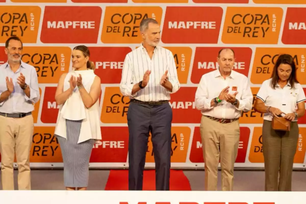 Cinc persones dretes aplaudint en un escenari amb un fons de logotips de la Copa del Rei i Mapfre. Cinc persones dretes aplaudint en un escenari amb un fons de logotips de la Copa del Rei i Mapfre.
