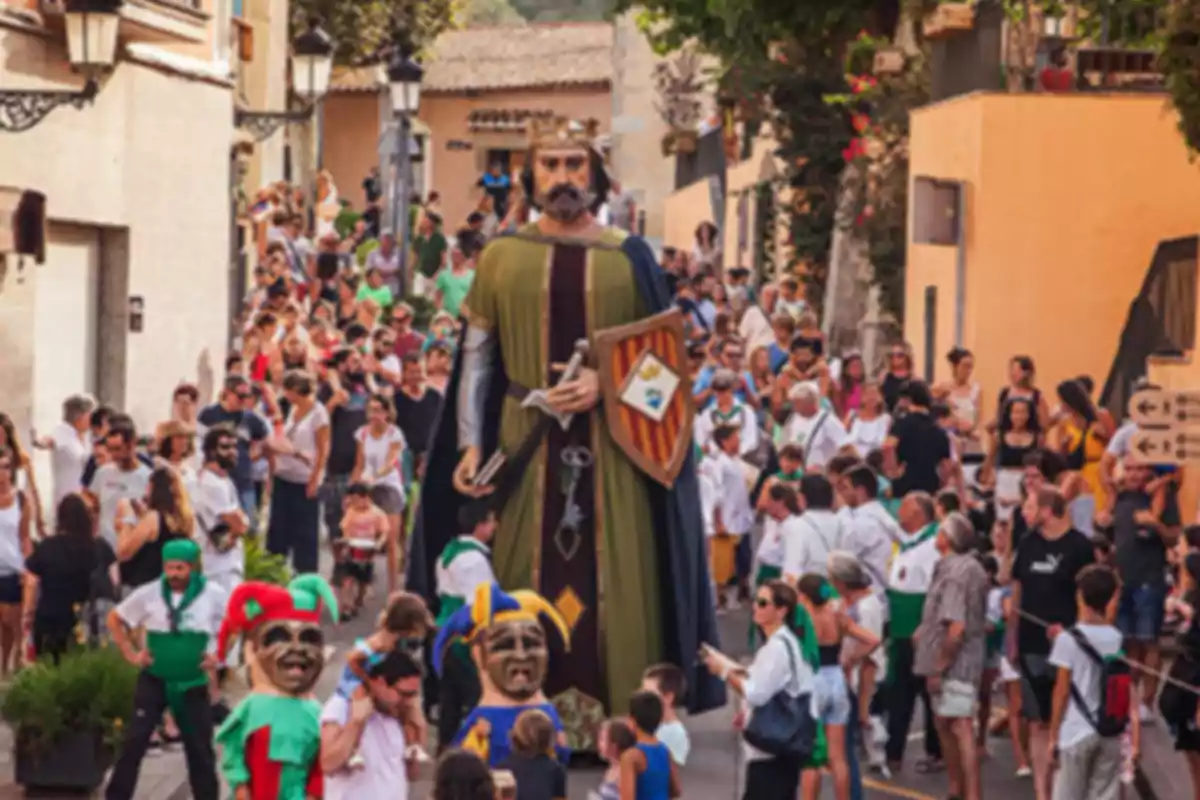 Desfile festivo en una calle con un gran muñeco de rey y personas disfrazadas rodeados de una multitud Desfile festivo en una calle con un gran muñeco de rey y personas disfrazadas rodeados de una multitud
