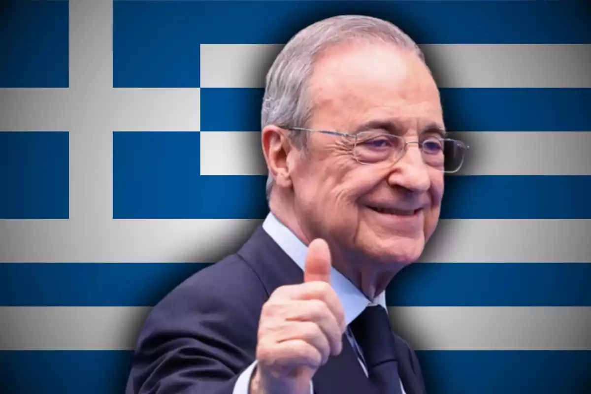 Hombre mayor con gafas y traje sonriendo y levantando el pulgar frente a una bandera de Grecia