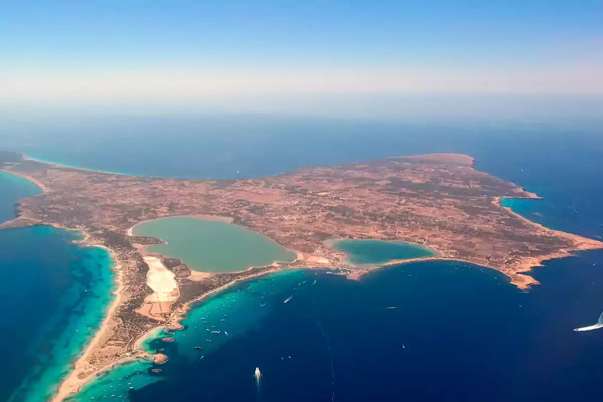 Vista aérea de una isla rodeada de mar azul con lagunas y zonas de vegetación y áreas áridas Vista aérea de una isla rodeada de mar azul con lagunas y zonas de vegetación y áreas áridas