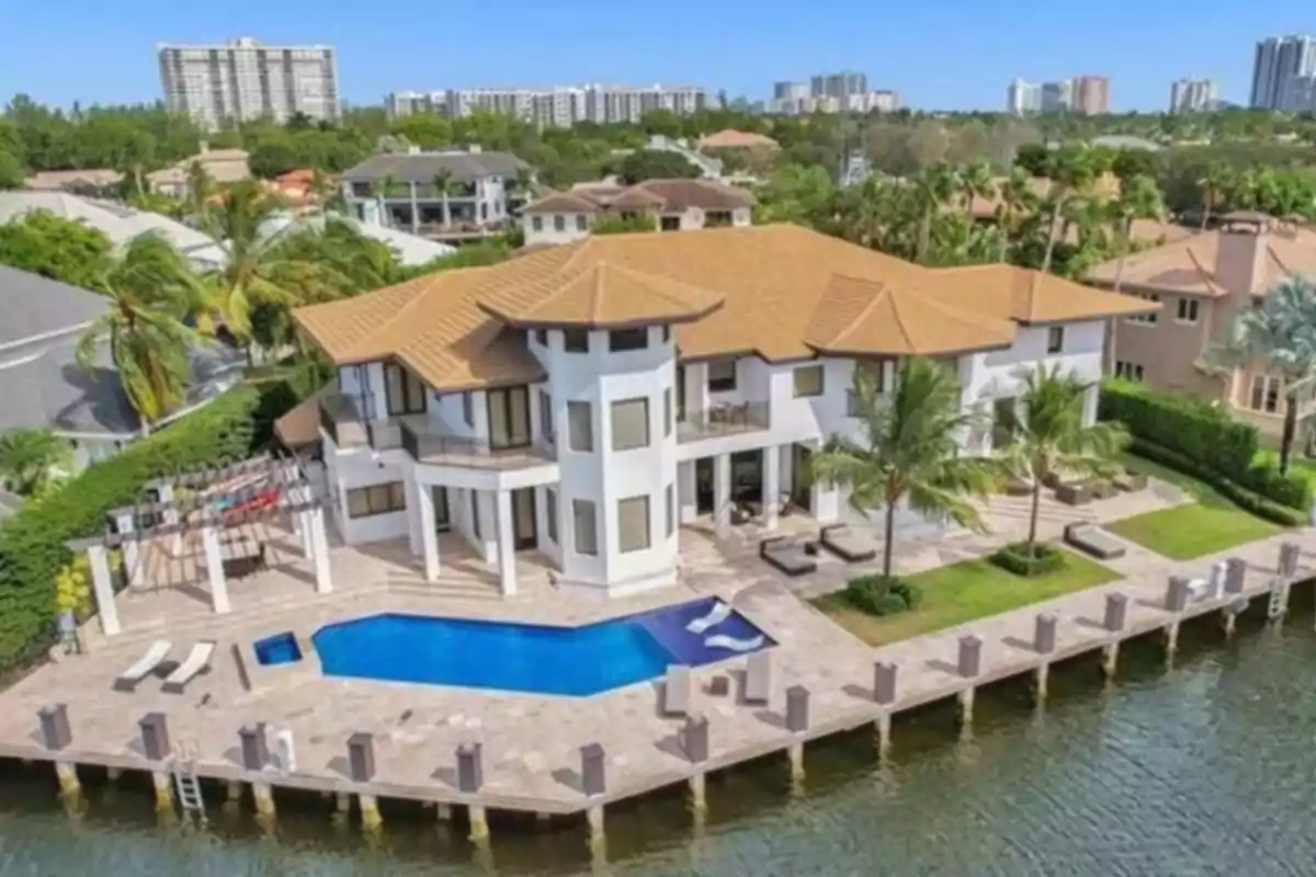 Modern two-story mansion with a pool and private dock by a canal, surrounded by palm trees and other luxurious houses in an exclusive neighborhood Modern two-story mansion with a pool and private dock by a canal, surrounded by palm trees and other luxurious houses in an exclusive neighborhood