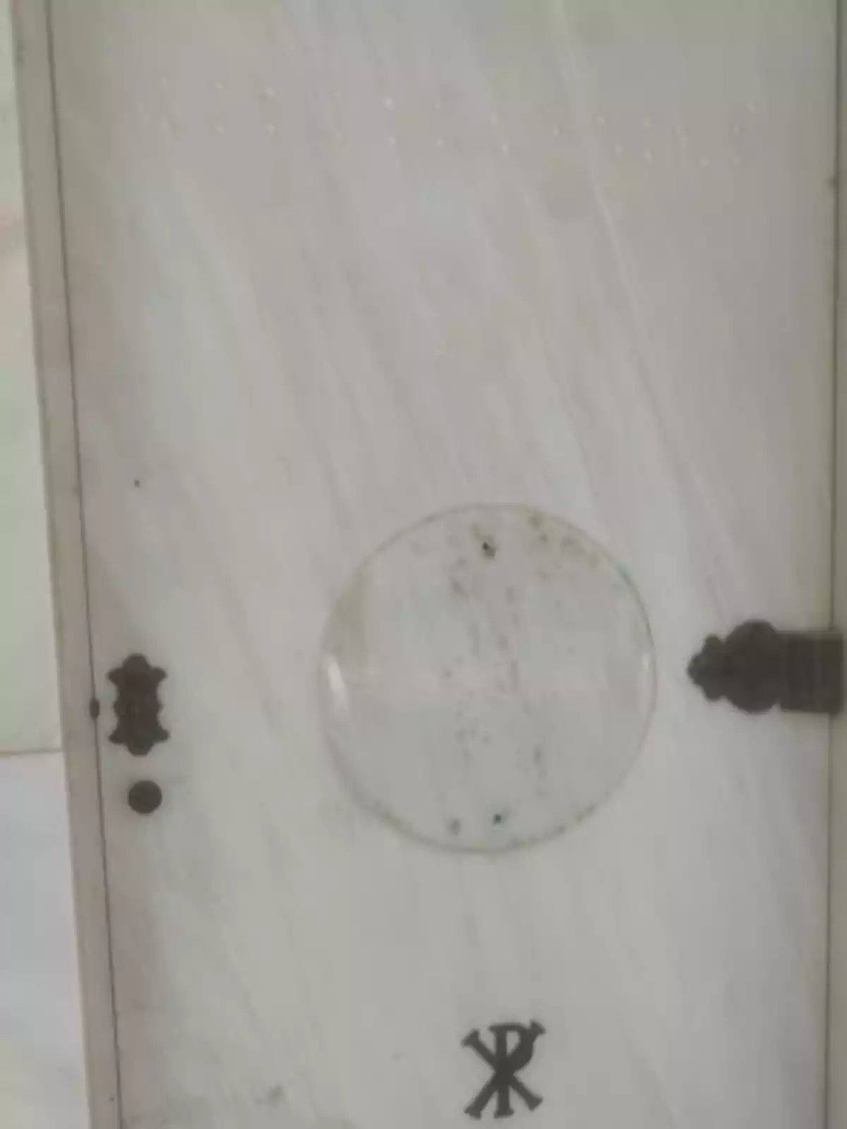 Tumba de mármol blanco con herrajes oscuros y símbolo cristiano en la parte inferior Tumba de mármol blanco con herrajes oscuros y símbolo cristiano en la parte inferior