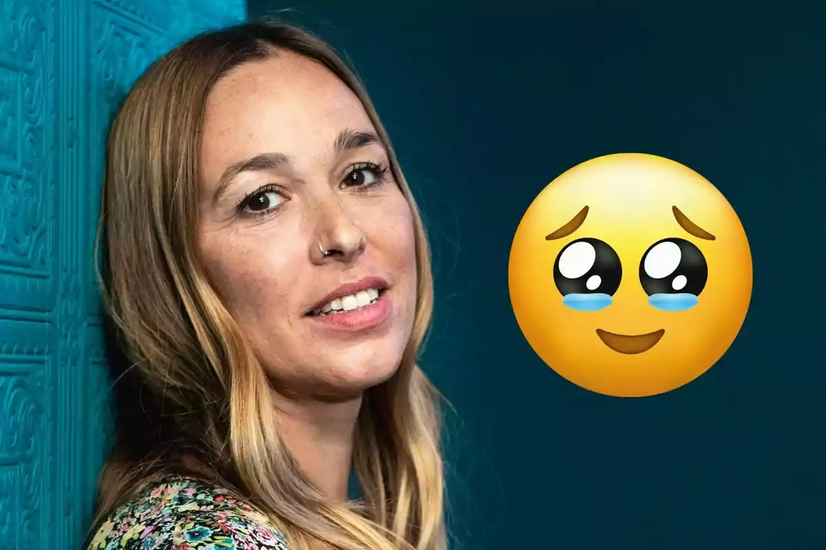 Dona de cabells llargs i rossos recolzada en una paret blava amb un emoji de carona amb llàgrimes i expressió tendra al seu costat