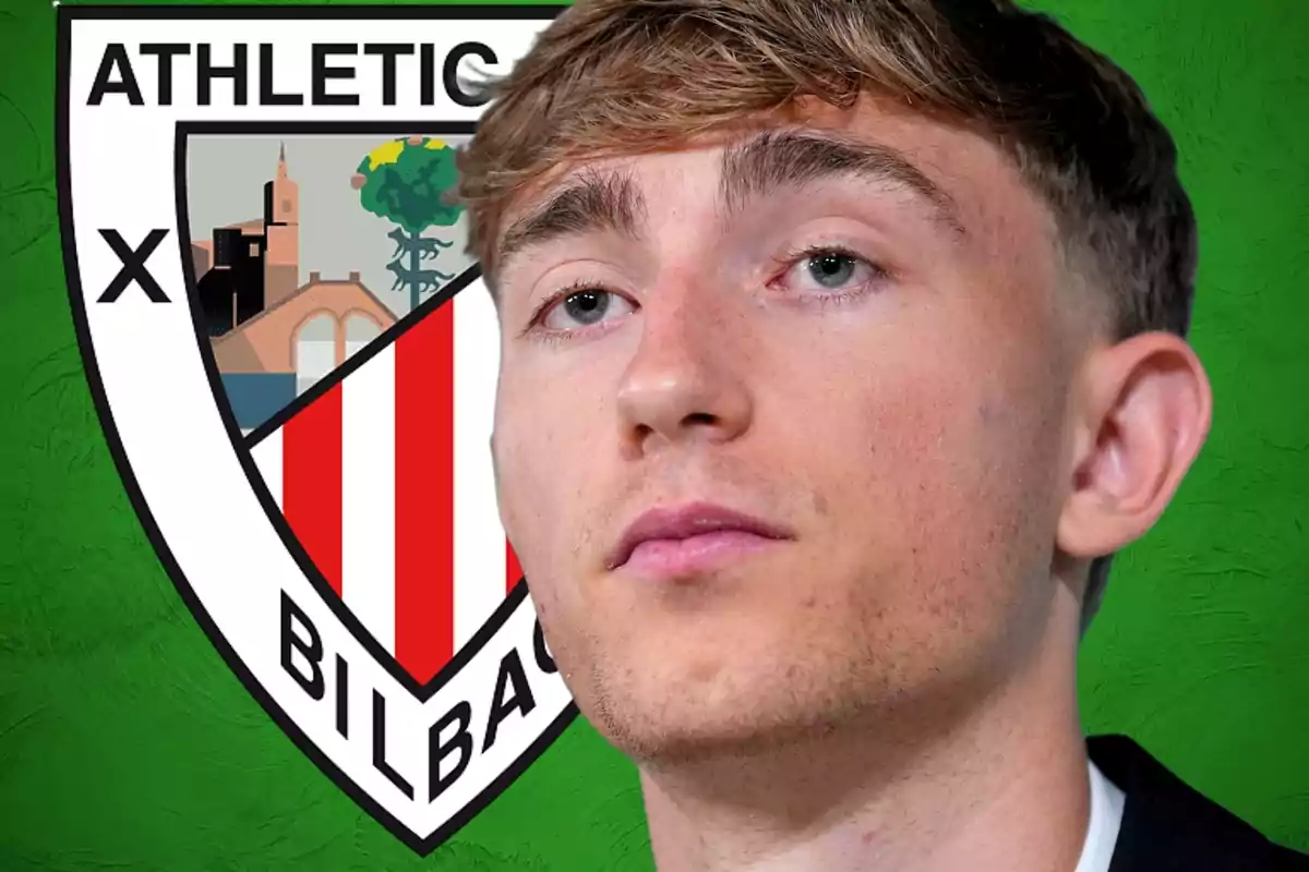 Joven de cabello claro posando frente al escudo del Athletic Club de Bilbao sobre un fondo verde