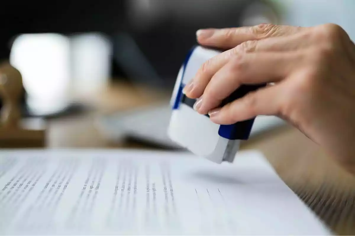 Mà estampant un segell en un document sobre una taula d’oficina