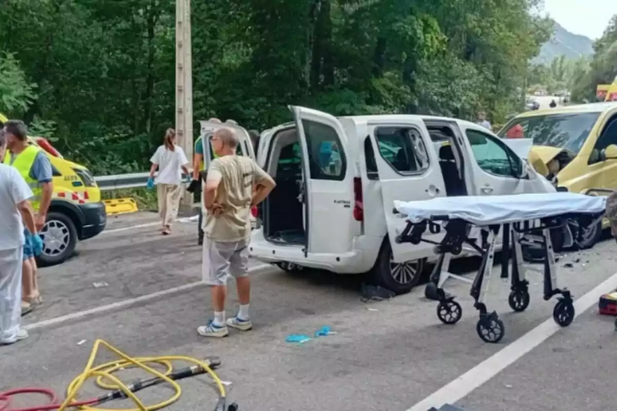 Diverses persones i serveis d’emergència atenen l’escena d’un accident viari a la C-631 entre una furgoneta blanca i un vehicle groc en una carretera envoltada d’arbres, amb una llitera buida en primer pla. Diverses persones i serveis d’emergència atenen l’escena d’un accident viari a la C-631 entre una furgoneta blanca i un vehicle groc en una carretera envoltada d’arbres, amb una llitera buida en primer pla.