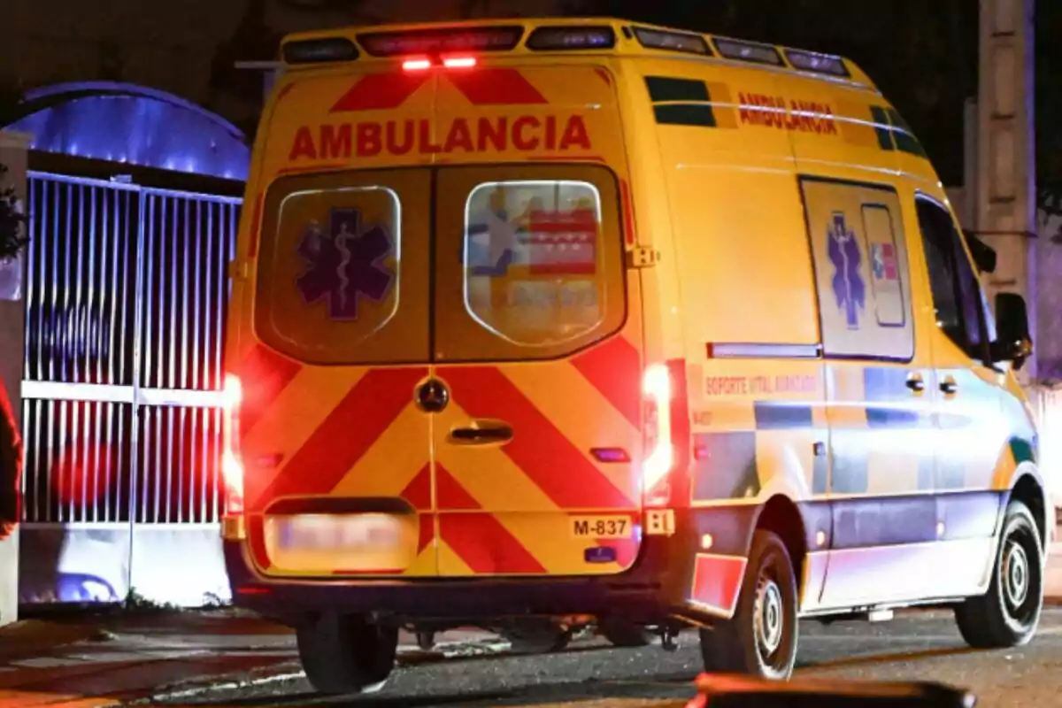 Ambulancia amarilla estacionada en la calle durante la noche con las luces traseras encendidas. Ambulancia amarilla estacionada en la calle durante la noche con las luces traseras encendidas.
