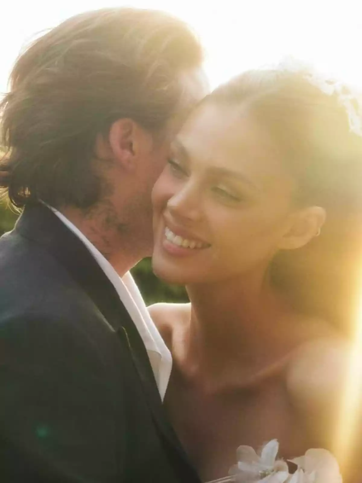 Couple hugging outdoors in warm light with the woman smiling happily Couple hugging outdoors in warm light with the woman smiling happily