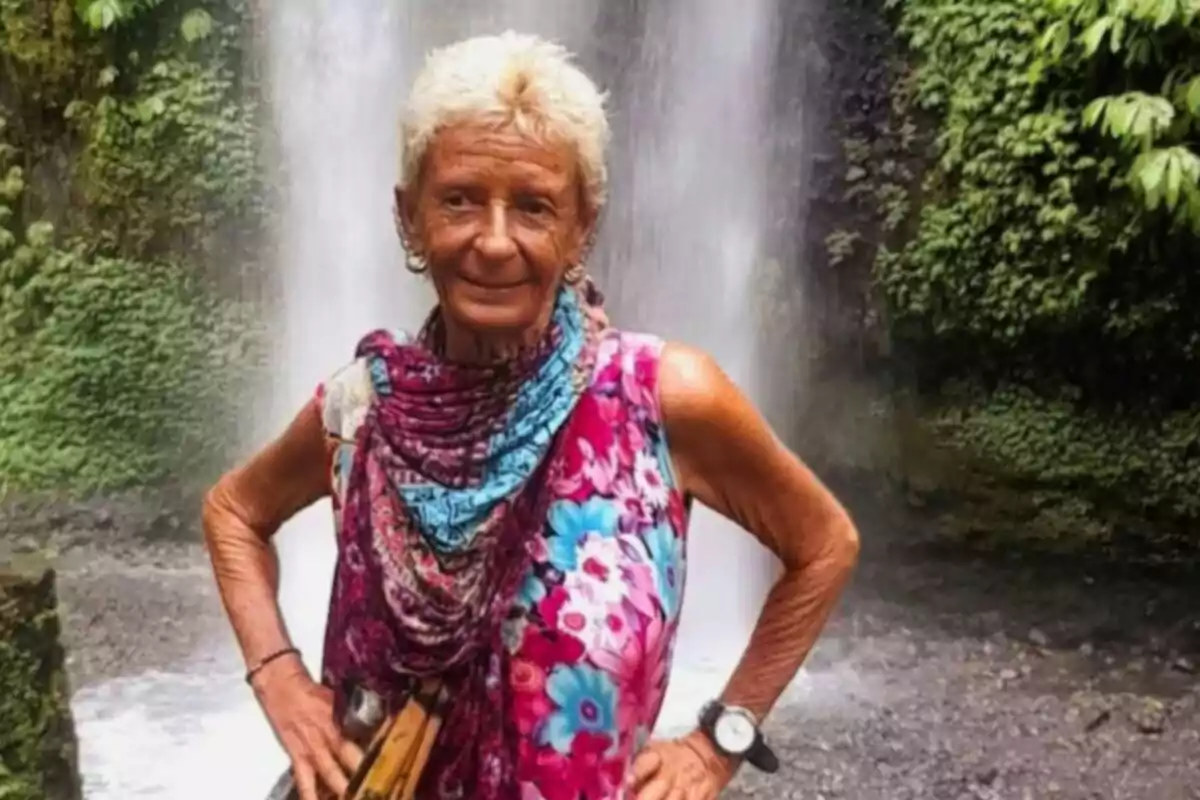 Matilde Muñoz Cazorla con cabello corto y canoso con vestido colorido y bufanda posando frente a una cascada rodeada de vegetación Matilde Muñoz Cazorla con cabello corto y canoso con vestido colorido y bufanda posando frente a una cascada rodeada de vegetación