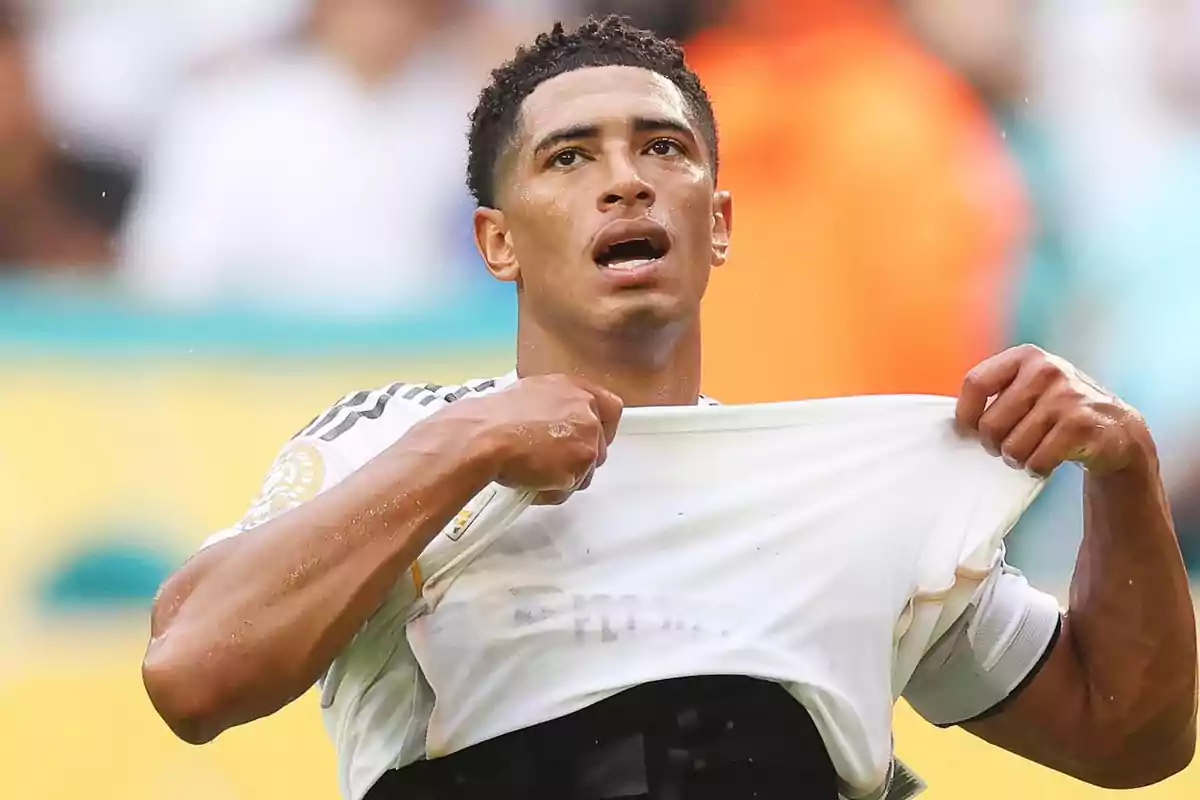 Soccer player lifting his white jersey during a match, showing an expression of effort Soccer player lifting his white jersey during a match, showing an expression of effort