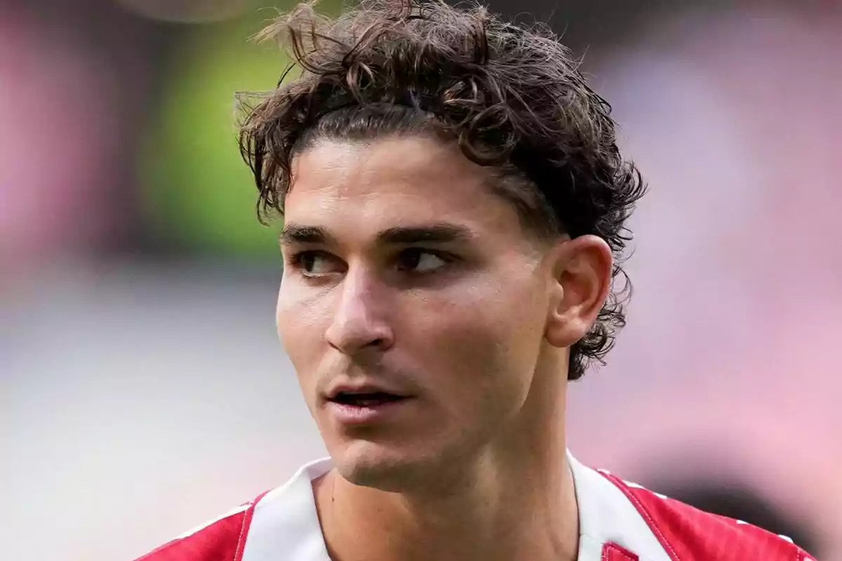 Jove futbolista amb cabell arrissat i cinta negra mirant cap a un costat durant un partit Jove futbolista amb cabell arrissat i cinta negra mirant cap a un costat durant un partit