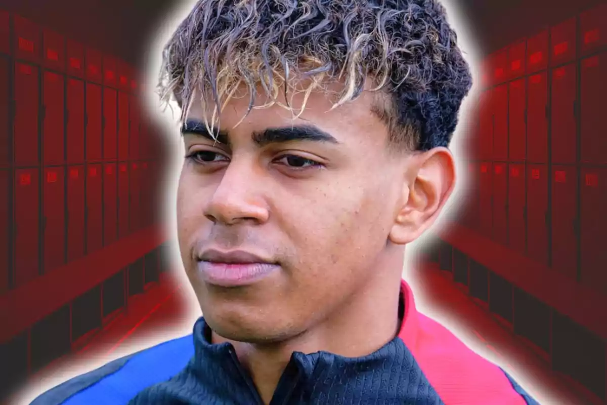 Young man with curly hair and blonde highlights wears a sports jacket and stands in front of a background of blurred red lockers.