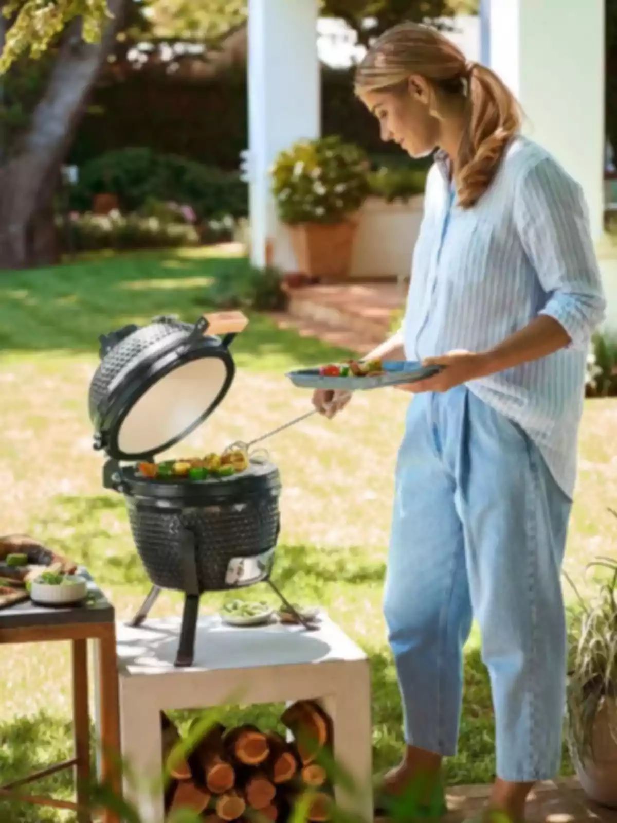 Woman grilling skewers on an outdoor barbecue in a garden on a sunny day Woman grilling skewers on an outdoor barbecue in a garden on a sunny day