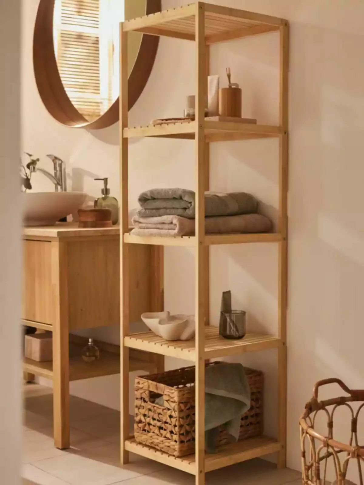 Estante de madera en un baño decorado con toallas dobladas, cestas de mimbre y accesorios de tocador junto a un espejo redondo y un lavabo Estante de madera en un baño decorado con toallas dobladas, cestas de mimbre y accesorios de tocador junto a un espejo redondo y un lavabo