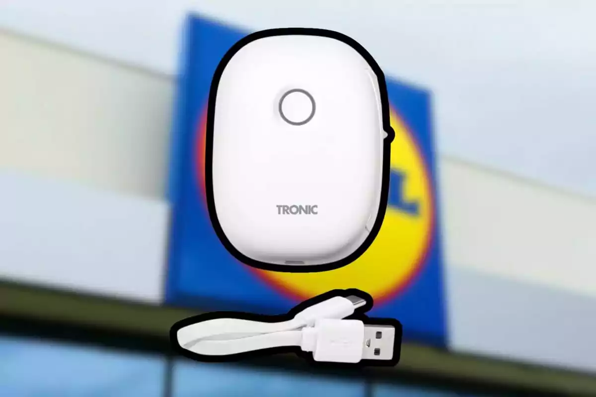 Dispositiu electrònic blanc de la marca Tronic al costat d’un cable USB sobre un fons desenfocat d’una botiga Lidl Dispositiu electrònic blanc de la marca Tronic al costat d’un cable USB sobre un fons desenfocat d’una botiga Lidl