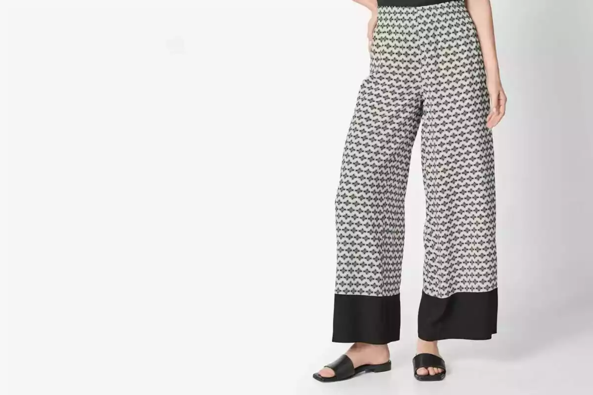 Woman wearing wide-leg black and white patterned pants with black sandals Woman wearing wide-leg black and white patterned pants with black sandals