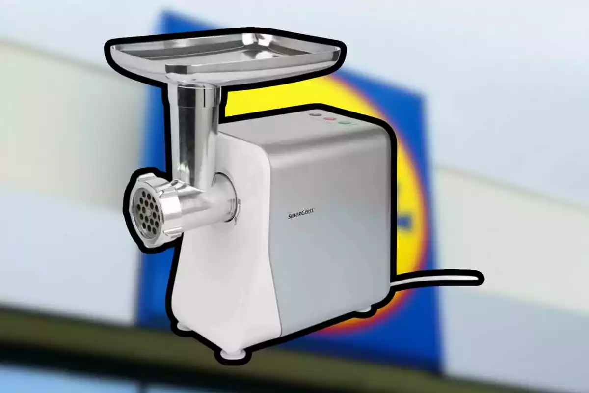 SilverCrest brand silver electric meat grinder against a blurred background of a supermarket sign. SilverCrest brand silver electric meat grinder against a blurred background of a supermarket sign.