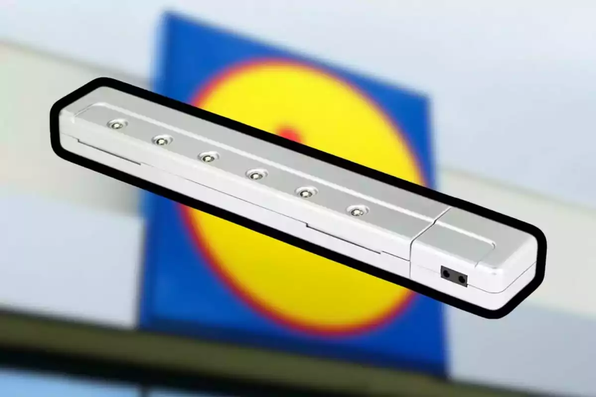 Lámpara LED portátil de color blanco con seis focos pequeños sobre un fondo desenfocado de un letrero azul y amarillo Lámpara LED portátil de color blanco con seis focos pequeños sobre un fondo desenfocado de un letrero azul y amarillo