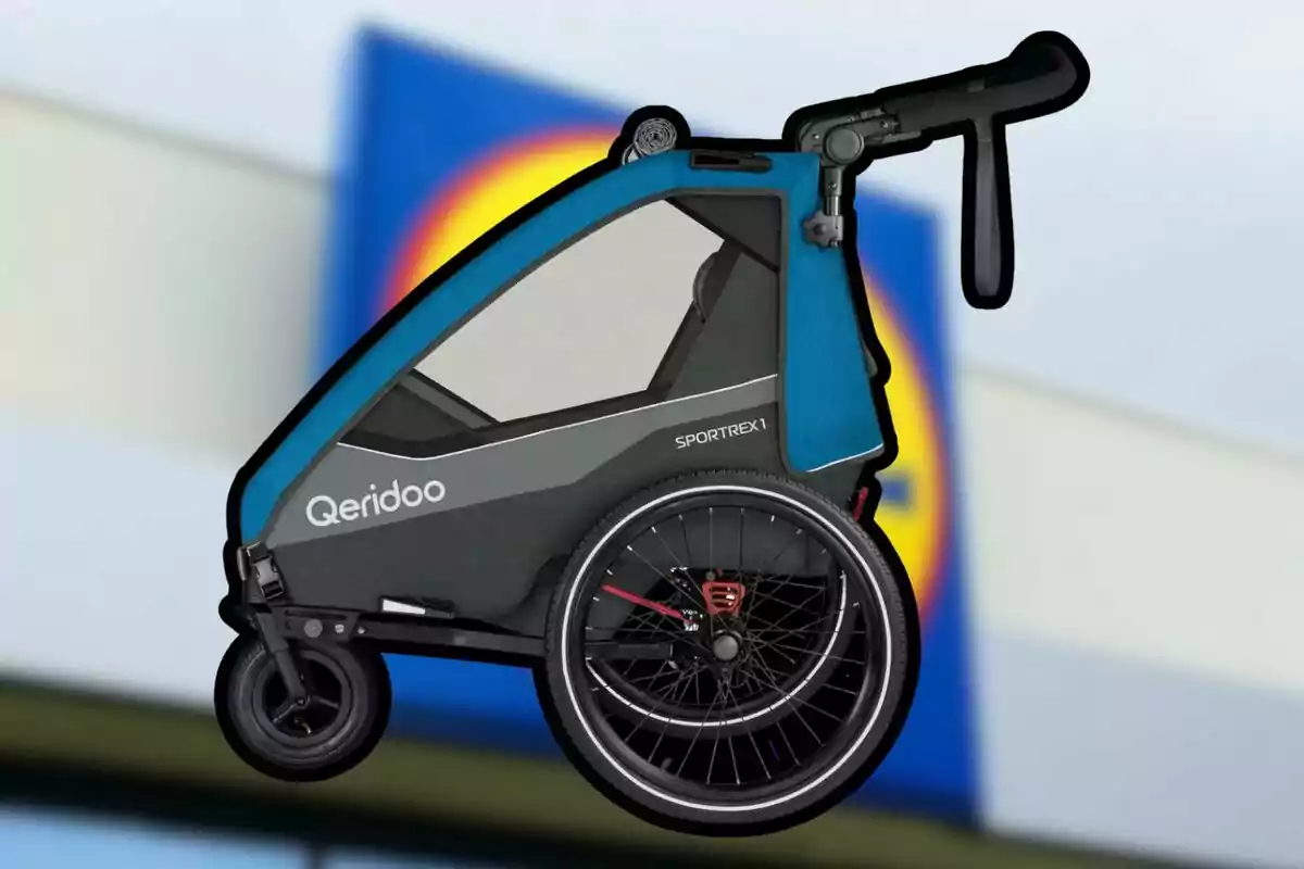 Remolque para bicicleta de color azul y negro con la marca Qeridoo frente a un fondo desenfocado de un supermercado. Remolque para bicicleta de color azul y negro con la marca Qeridoo frente a un fondo desenfocado de un supermercado.