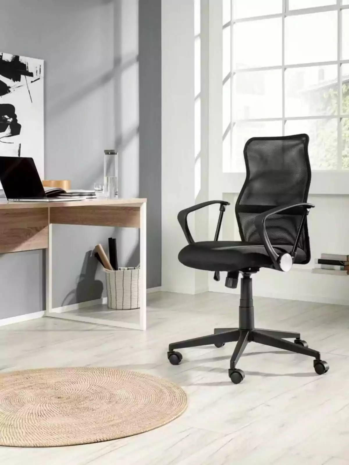 Silla de oficina negra con respaldo de malla en un espacio de trabajo moderno y luminoso junto a un escritorio de madera y una ventana grande Silla de oficina negra con respaldo de malla en un espacio de trabajo moderno y luminoso junto a un escritorio de madera y una ventana grande