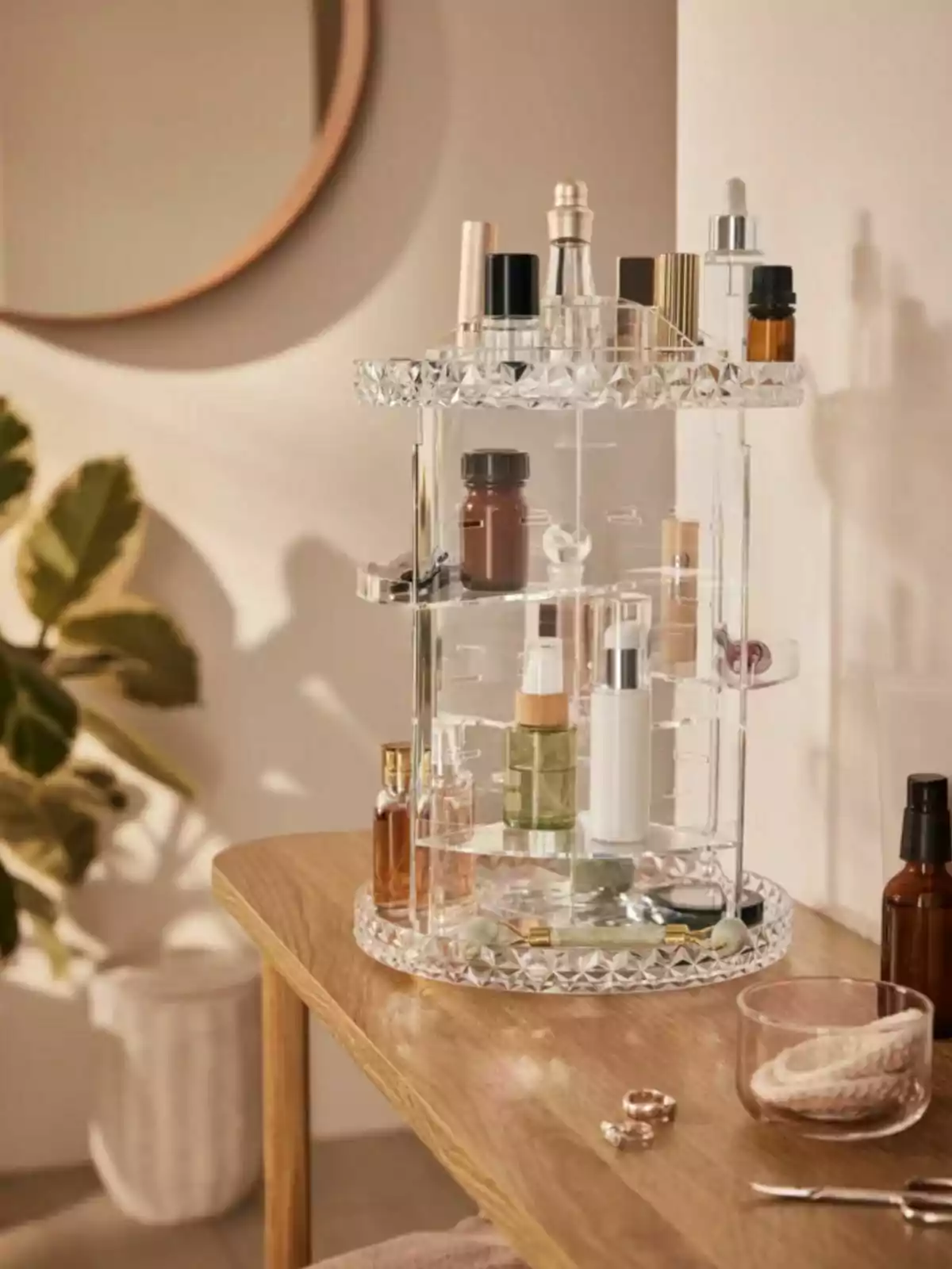 Clear acrylic rotating organizer with various cosmetic jars and personal care products on a wooden table in a bright, decorative setting Clear acrylic rotating organizer with various cosmetic jars and personal care products on a wooden table in a bright, decorative setting