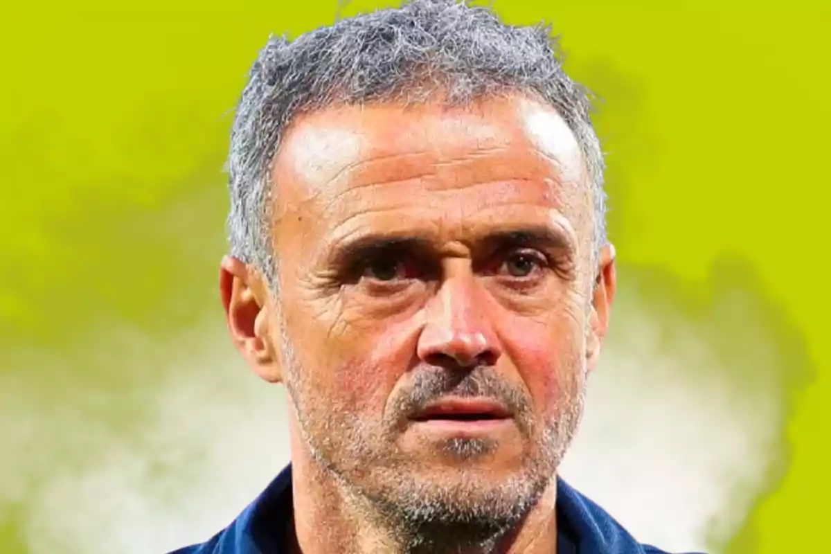 Gray-haired man with a short beard and a serious expression against a blurred yellow background