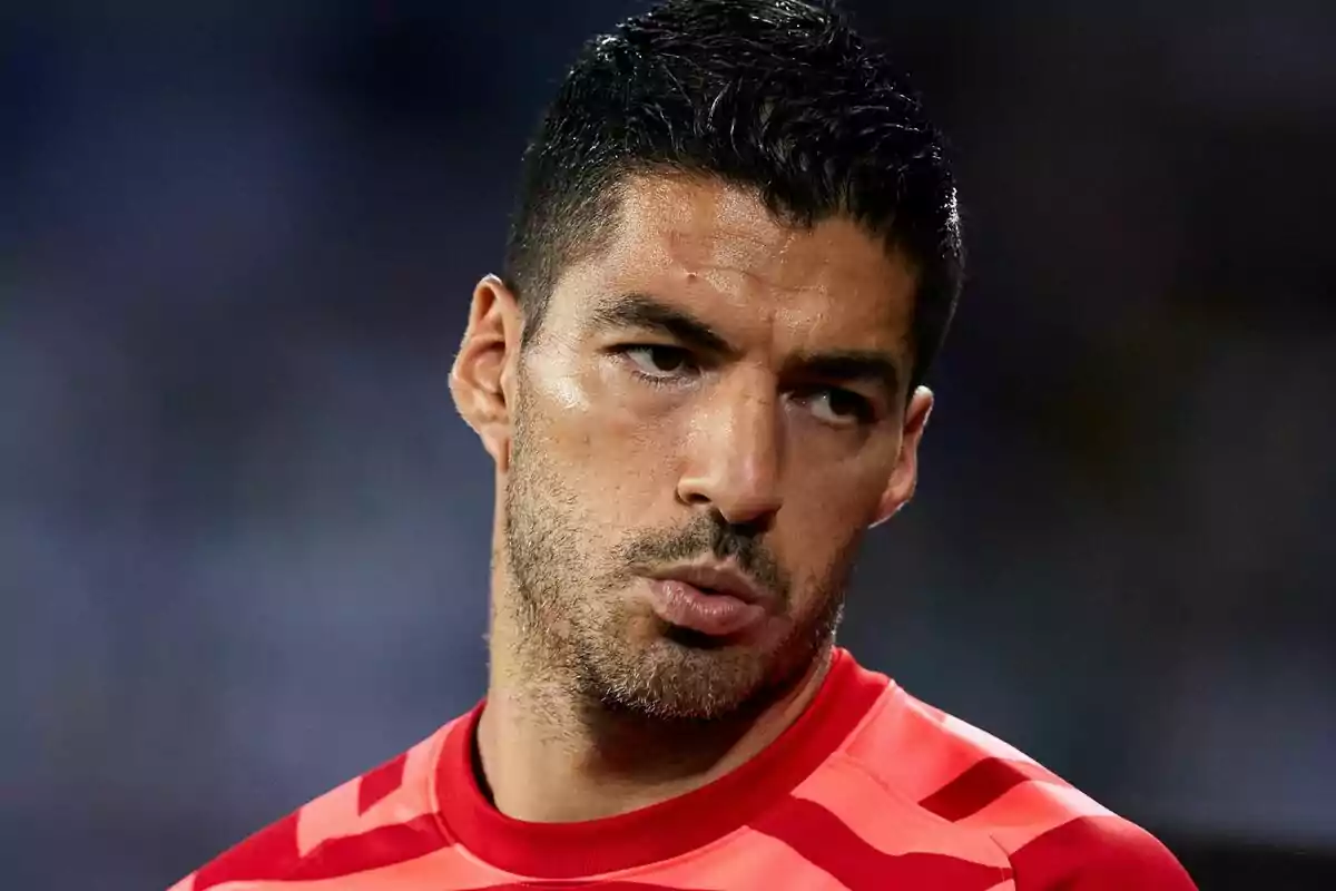 Man in a red sports jersey looking to the side with a serious expression Man in a red sports jersey looking to the side with a serious expression