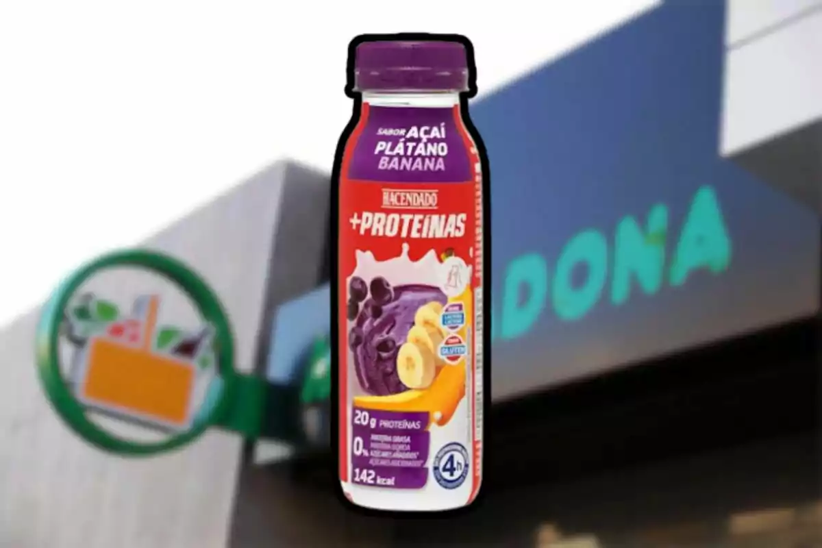 Ampolla de batut de proteïnes sabor açaí, plàtan i banana de la marca Hacendado davant d’un supermercat Mercadona desenfocat Ampolla de batut de proteïnes sabor açaí, plàtan i banana de la marca Hacendado davant d’un supermercat Mercadona desenfocat