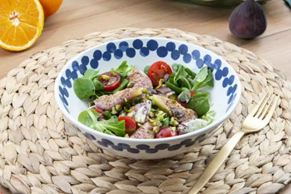 Ensalada fresca con tomates cherry, hojas verdes y trozos de pescado servida en un plato decorado sobre un mantel tejido, acompañada de un tenedor dorado y frutas al fondo Ensalada fresca con tomates cherry, hojas verdes y trozos de pescado servida en un plato decorado sobre un mantel tejido, acompañada de un tenedor dorado y frutas al fondo